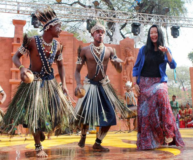 A tourist dances with folk artists at the International Crafts Mela in Faridabad, Haryana, on February 6