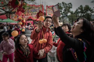 A family take pictures of their wishes tied to plastic oranges hanging from the branches of a special tree in the remote village of Lam Tsuen of Hong Kong new territories