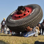 A man trying to lift the tyre on his shoulders at the 79th Kila Raipur Sports Festival at Kila Raipur village, Ludhiana