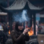A woman burns incense as she prays for good fortune at the Jade Buddha Temple on the third day of the Chinese Lunar New Year in Shanghai