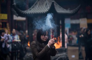 A woman burns incense as she prays for good fortune at the Jade Buddha Temple on the third day of the Chinese Lunar New Year in Shanghai