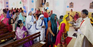 A Christian priest offers sweets to devotees on Easter at St Francis Church in Bhopal