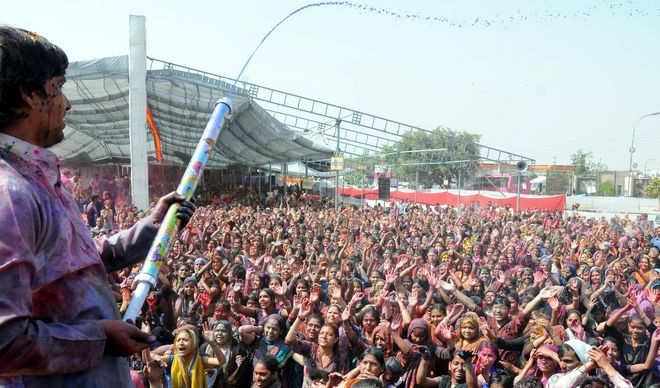 People dance as colours water is sprayed during Holi celebrations in East Delhi