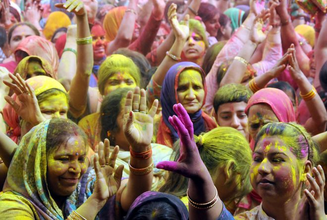 Women dance as colours water is sprayed during Holi celebrations in East Delhi