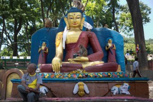A man sits next to a statue of Buddha during Buddha Purnima celebrations outside the Boudhanath Stupa in Kathmandu on May 4, 2015.