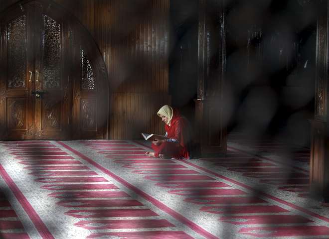 A Kashmiri Muslim woman reads the Koran inside the shrine of Sufi Saint Sheikh Hamzah Makhdoomi during the holy month of Ramadan in Srinagar
