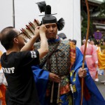 A Shinto studies specialty student in traditional costume is helped by a staff to prepare before a ritual for the Kanda festival at the Kanda-Myojin shrine in Tokyo on May 9, 2015.