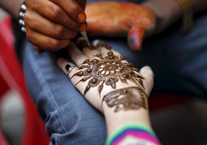 A girl gets her hand decorated with henna paste at a marketplace ahead of the Eid al-Adha festival in Srinagar on September 23, 2015