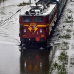 A train runs on track sunbmerged in water after heavy rains lash Mumbai on June 19, 2015