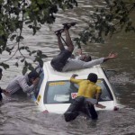 A vehicle stuck on a road even as some boys make the most of the heavy rain and the flooding in Mumbai on June 19, 2015