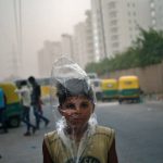 A young boy uses a plastic bag to protect himself from a dust storm in New Delhi, May 23, 2016