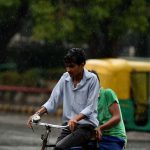 An Indian cyclist makes his way during a rain shower in New Delhi on May 23
