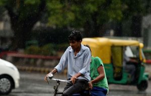 An Indian cyclist makes his way during a rain shower in New Delhi on May 23