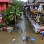 Indian pedestrians wade through a waterlogged neighbourhood in Mumbai on June 19, 2015