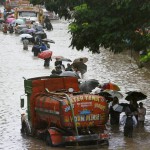 People walk across a waterlogged road after heavy rains i Mumbai on June 19, 2015