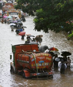 People walk across a waterlogged road after heavy rains i Mumbai on June 19, 2015