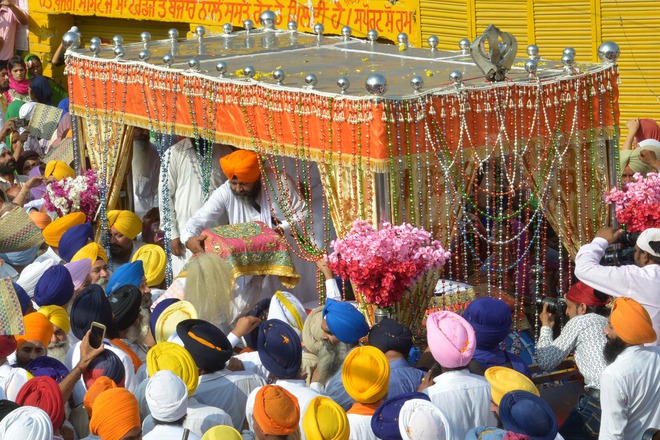 A Sikh priest (centre) places the Guru Granth Sahib onto a palanquin during a procession for Guru Nanak Dev's marriage anniversary from the Gurdwara Sri Dehra Sahib temple to the Kandh Sahib temple in Batala, some 45 km (28 miles) northeast of Amritsar on September 20, 2015