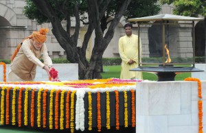 In this handout photograph released by The Indian Press Informatuion Bureau (PIB) on August 15, 2015, India's Prime Minister Narendra Modi (L) is watched by an official as he scatters rose petals while paying his respects at the Samadhi of Mahatma Gandhi at Rajghat in New Delhi, on the occasion of India's Independence Day.