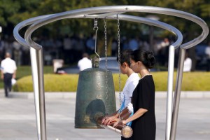 People ring a bell to mark the moment when an atom bomb exploded over Hiroshima 70 years ago during a commemoration ceremony at Peace Memorial Park in Hiroshima, August 6, 2015. The US dropped an atomic bomb at Hiroshima on August 6, 1945, killing about 140,000 by the end of the year in a city of 350,000 residents. It was the world's first nuclear attack.