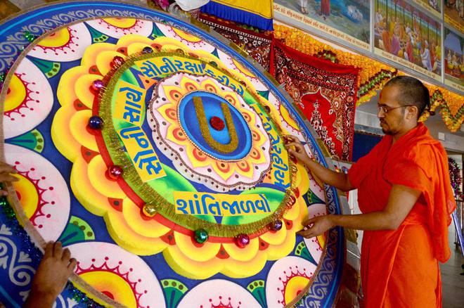 Priest of Kumkum Swaminarayan temple gives final touches to a huge ‘Rakhi’ on a day before Raksha Bandhan in Ahmedabad on August 28, 2015. The rakhi had various peace messages in view of the recent incidents of violence