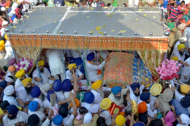 Sikh devotees pay their respects at the Palki Sahib carrying the Guru Granth Sahib during a procession for Guru Nanak Dev's marriage anniversary from the Gurdwara Sri Dehra Sahib temple to the Kandh Sahib temple in Batala, some 45 km (28 miles) northeast of Amritsar on September 20, 2015