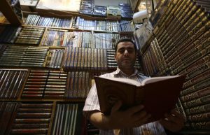 A Syrian man reads a copy of the Quran, Muslim's holy book, at a book stall in a market in the capital Damascus on June 5, as people prepare for the holy month of Ramadan due to start this week.