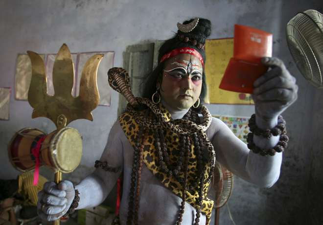 A man dressed as Hindu Lord Shiva looks into the mirror as he gets ready to take part in a religious procession on the eve of Janmashtami, a festival that marks the birth anniversary of Hindu Lord Krishna, in Amritsar on September 4, 2015