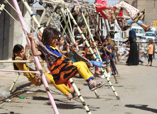 Iraqi children play on swings in the capital Baghdad on the second day of the Muslim Eid al-Adha (Feast of the Sacrifice) holiday on September 25, 2015