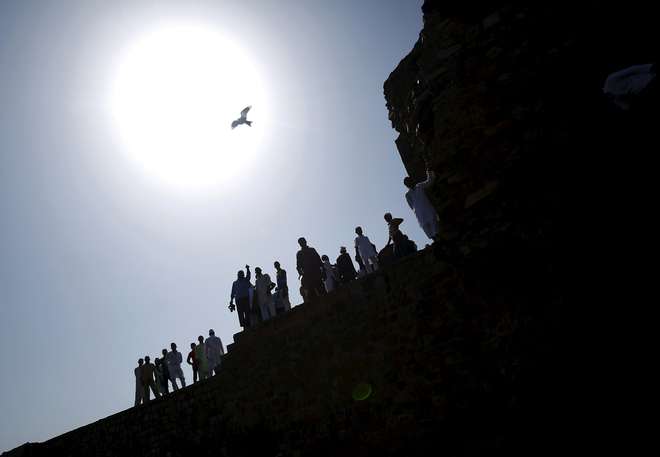 Muslims are silhouetted against the rising sun as they stand at the ruins of the Feroz Shah Kotla mosque after offering Eid al-Adha prayers in New Delhi on September 25, 2015