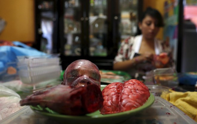 A bloody zombie baby head, brain and a hand made of gummy candy and red jelly are pictured as a woman works (rear) at the Zombie Gourmet homemade candy manufacturer on the outskirts of Mexico City on October 30, 2015