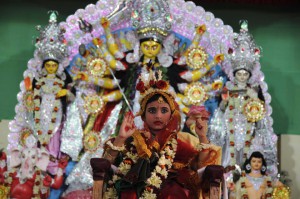 A young Hindu unmarried girl, known as a 'kumari', and dressed as the Hindu goddess Durga, puts her hand up during a ritual for the Durga Puja festival at Ramakrishna Mission in Agartala on October 21, 2015