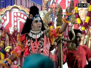 Artist dressed as Lord Shiva performing a dance item during a Mata Ki Chowki celebration
