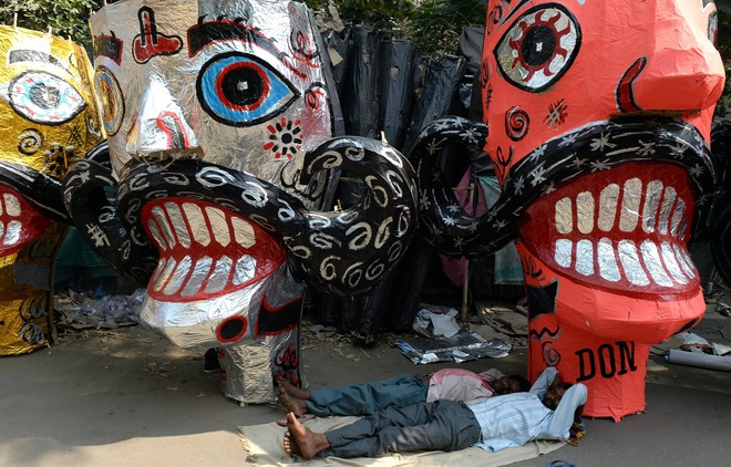 Labourers rest by the effigies of Hindu demon King Ravana, displayed for sale at a roadside in New Delhi on October 20, 2015, ahead of the Hindu festival of Dussehra
