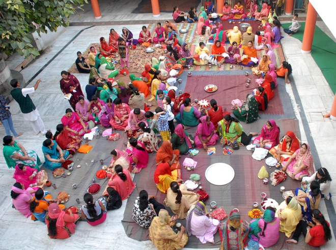 Married women exchange thalis while offering prayers for their husbands’ welfare, prosperity, and longevity on Karwa Chauth, a traditional Hindu festival celebrated in northern India during which married women fast one whole day and offer prayers to the moon for the welfare, prosperity, and longevity of their husbands, at a temple in Amritsar on October 30, 2015