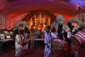 Musicians play drums as a Hindu priest offers evening prayer in front of an idol of the Goddess Durga in New Delhi on late October 20,2015