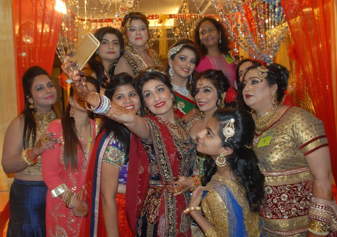 Women click selfies during a function organised to mark Karwa Chauth, a traditional Hindu festival celebrated in northern India during which married women fast one whole day and offer prayers to the moon for the welfare, prosperity, and longevity of their husbands, in Amritsar on October 30, 2015