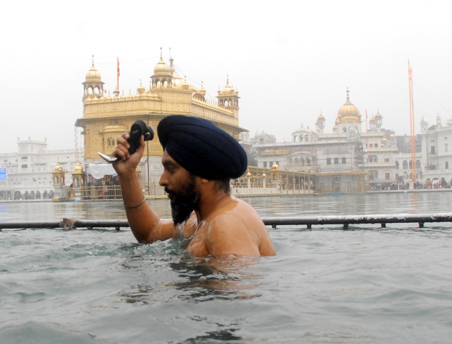 A Sikh devotee takes a dip at the Golden Temple on the birth anniversary Guru Gobind Singh in Amritsar on January 16, 2016