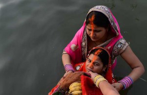 Hindu devotees hold offerings before prayers during the Chhat festival on the banks of the river Yamuna in New Delhi on November 17, 2015
