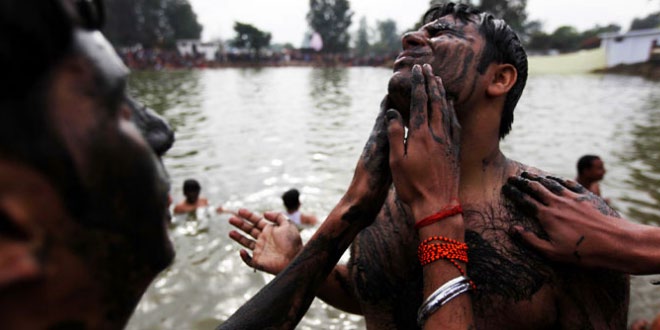 Indian Hindu devotees smear themselves with mud before taking a holy dip
