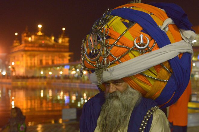 Sikh Nihang (a traditional Sikh religious warrior) Baba 'Avtar' Singh wears an oversized giant traditional turban as he pay respects at the Golden temple in Amritsar on November 10,2015 on the eve of the Indian festival of Diwali, the festival of lights