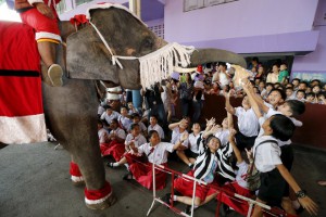 Children walk past elephants as they arrive in school to attend a Christmas festival in Ayutthaya, Thailand, on December 24, 2015