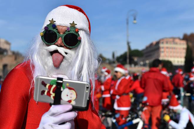 People gather near the ancient Colosseo to take part in a Santa Claus rally for charity on December 13, 2015 in Rome