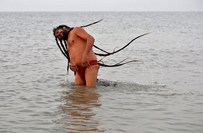 A Sadhu takes a dip at the confluence of the river Ganges and the Bay of Bengal on the occasion of Makar Sankranti festival at Sagar Island, south of Kolkata, on January 14, 2017