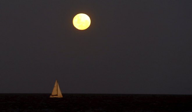 A boat sails on the waters of the Rio de La Plata as a full moon rises over the Buenos Aires sky on December 25, 2015. Its appearance marks the first full moon to happen on Christmas day since 1977, and this phenomenon will not happen again until 2034, according to weather reports