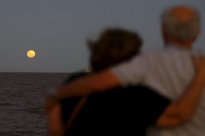 A couple watches a full moon rising over the Buenos Aires sky on December 25, 2015.