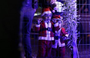 Iraqi Christian children, who fled the violence with their families in the northern city of Mosul after Islamic State (IS) group militants took control of the area, stand behind a fence during a Christmas eve mass at the Syriac Catholic church in the Ashti camp in Arbil, the capital of the autonomous Kurdish region of northern Iraq, on December 24, 2015