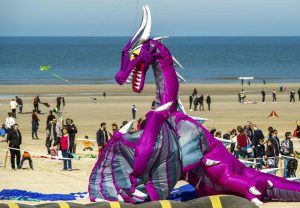 People prepare to fly a kite in the shape of a dragon during the 30th International Kite Festival in Berck-sur-Mer in northern France on April 12, 2016