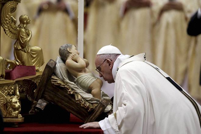 Pope Francis kisses a statue of Baby Jesus as he celebrates the Christmas Eve Mass in St. Peter's Basilica at the Vatican on December 24, 2015