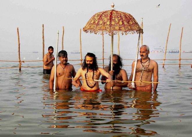 Priests along with devotees perform Ganga Arti after taking a holy dip in the Ganges on Makar Sankranti during Magh Mela festival in Allahabad on January 15, 2016