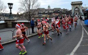 Runners wearing Santa Claus costumes, bonnets and bathing suits warm up before taking part in the 13th Santa Claus Run in Budapest on December 11, 2016